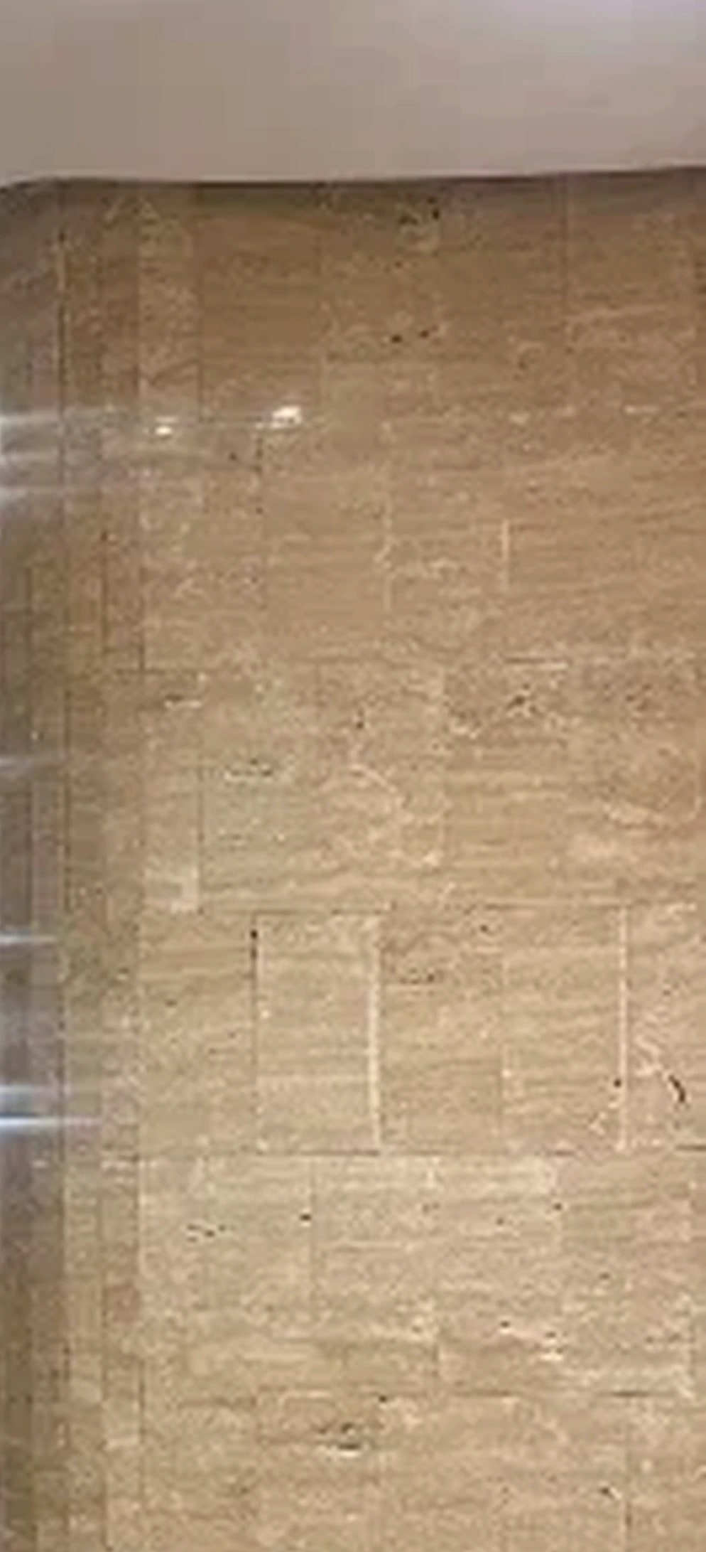 A travertine wall at the entrance, raked by warm light.