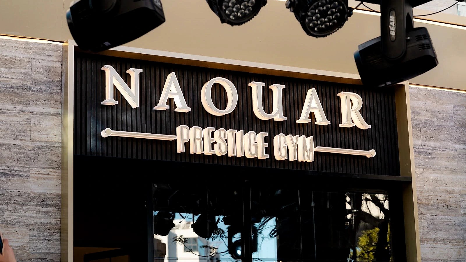 The illuminated Naouar Prestige Gym sign above the club's entrance on the street.
