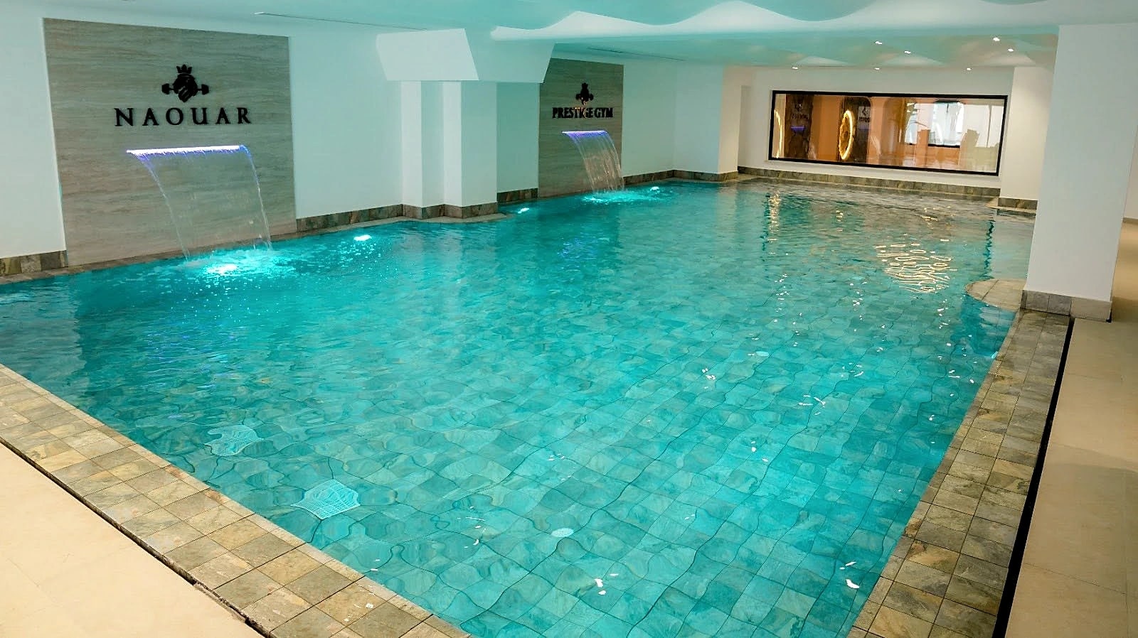The indoor swimming pool seen along its length, the Naouar name on the far wall.