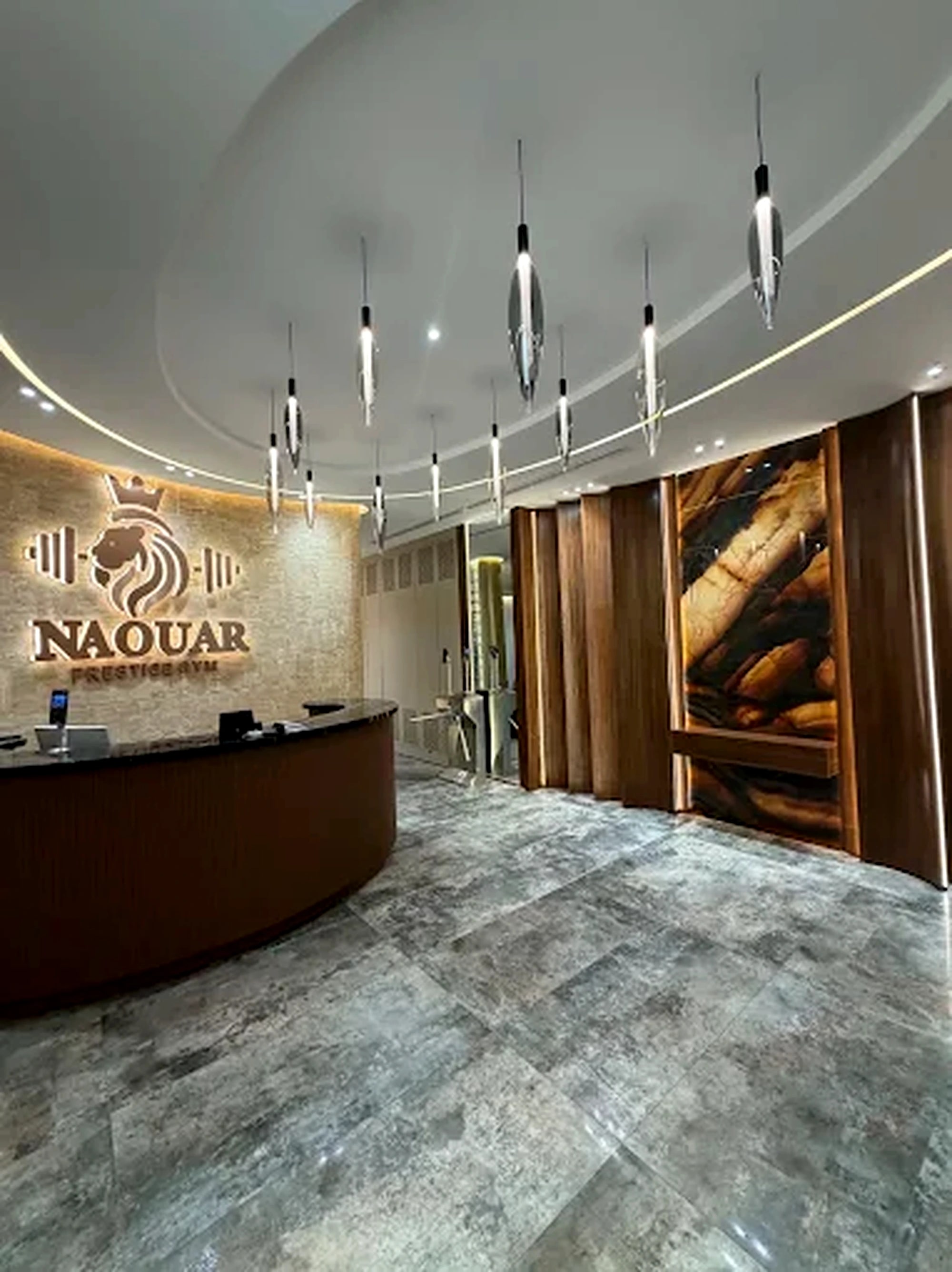 The reception desk at Naouar Prestige Gym beneath the club's crowned lion mark, lit on a stone wall.