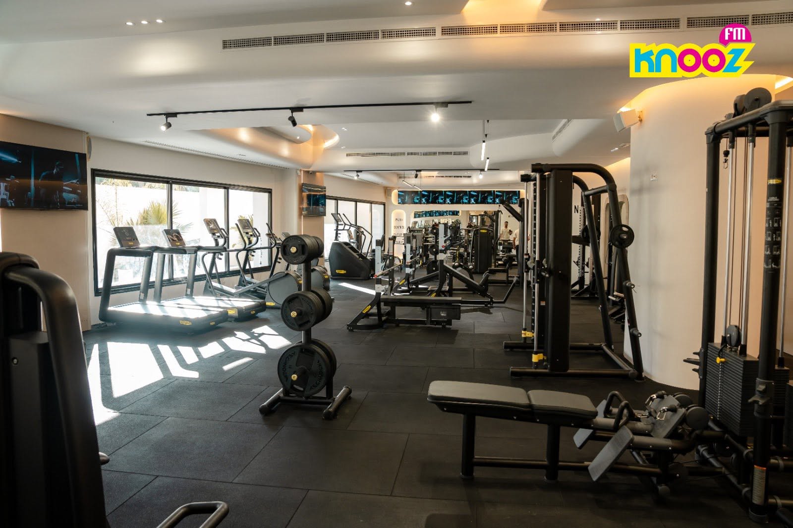 A wide view across the training floor at Naouar Prestige Gym, showing resistance machines, free weights and the cardio zone under daylight.